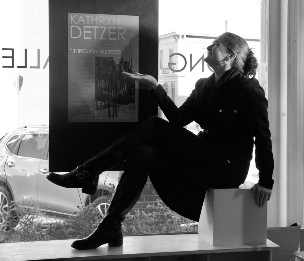 LRG_Womaniquin - Rachel Obbard The silhouette of a woman sitting in a window gesturing to a poster promoting an art show for Kathy Detzer at Long RIver Gallery.