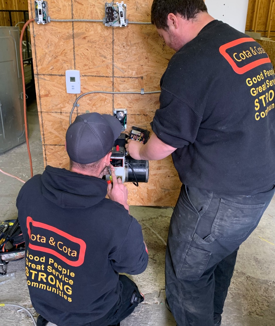 Two technicians from Cota & Cota installing gas lines in a house.